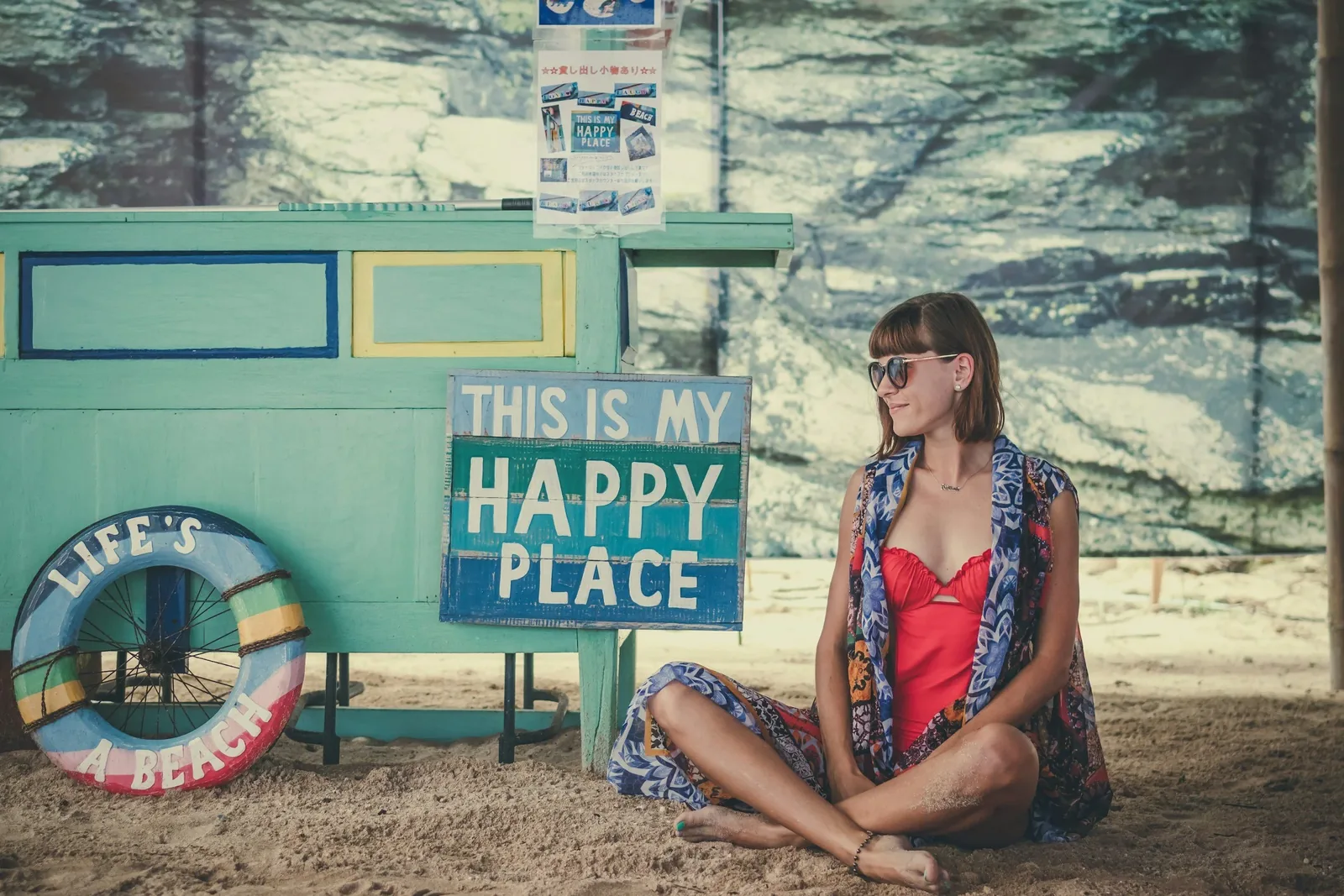 Woman sitting peacefully with a 'My Happy Place' sign, representing finding joy and inner peace during the holiday season on a fertility journey.